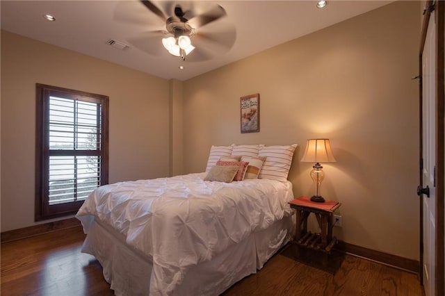 bedroom with baseboards, visible vents, and wood finished floors