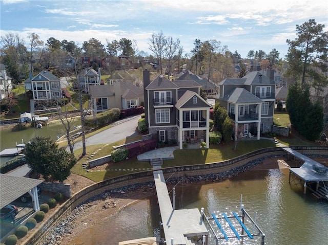 back of house with a water view, a patio area, a residential view, and a yard