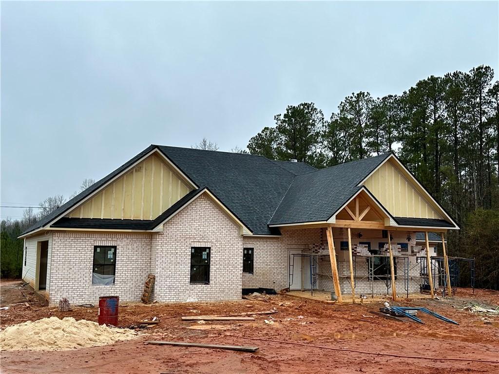 view of front of home featuring brick siding, board and batten siding, and a shingled roof