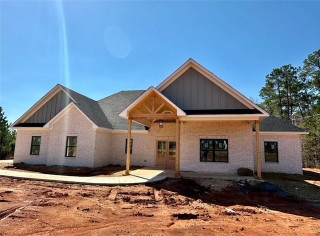 view of front facade featuring brick siding, board and batten siding, and a patio