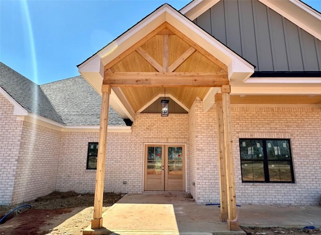 doorway to property with brick siding, french doors, and board and batten siding