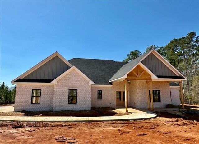 view of front of house featuring brick siding, a patio area, and board and batten siding