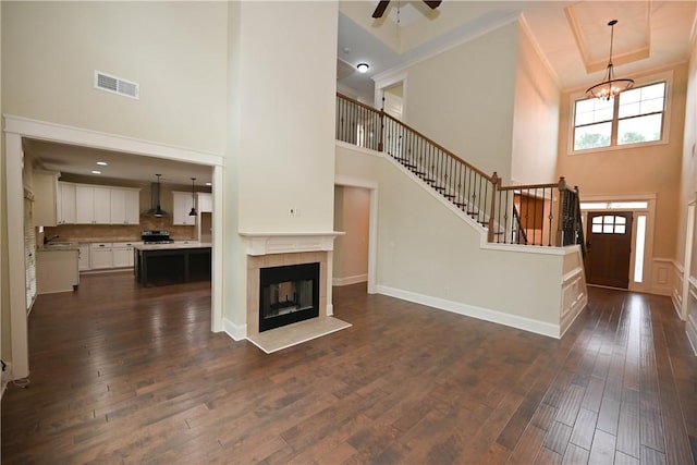 2228 Morgan Dr, Auburn, AL 36830 - unfurnished living room with a towering ceiling, a chandelier, dark wood-style floors, ceiling fan, and a tiled fireplace