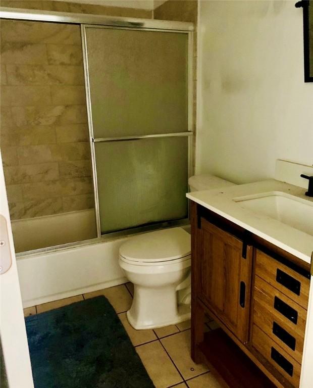 full bathroom featuring shower / bath combination with glass door, tile patterned floors, vanity, and toilet