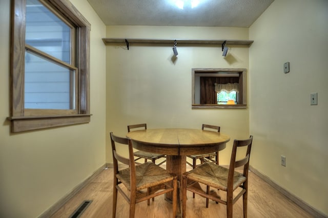 dining space with a textured ceiling and light wood-type flooring