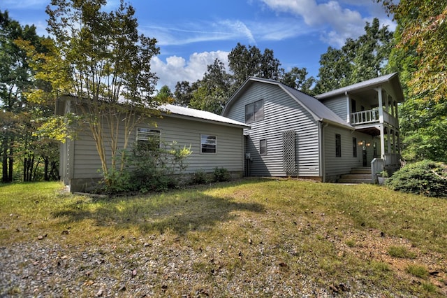 rear view of house featuring a balcony and a lawn