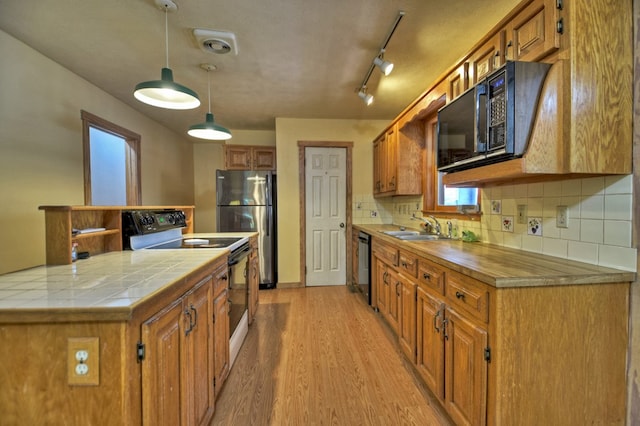 kitchen featuring backsplash, pendant lighting, stainless steel appliances, light hardwood / wood-style flooring, and sink