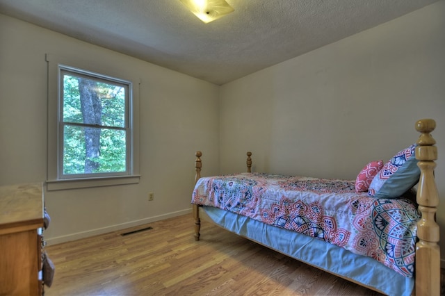 bedroom featuring wood-type flooring and a textured ceiling