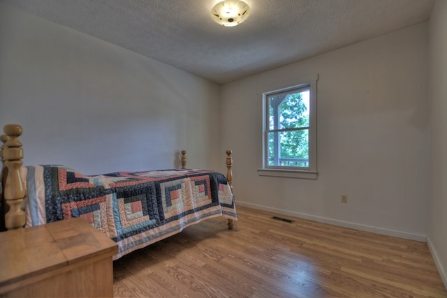 bedroom with a textured ceiling and hardwood / wood-style flooring