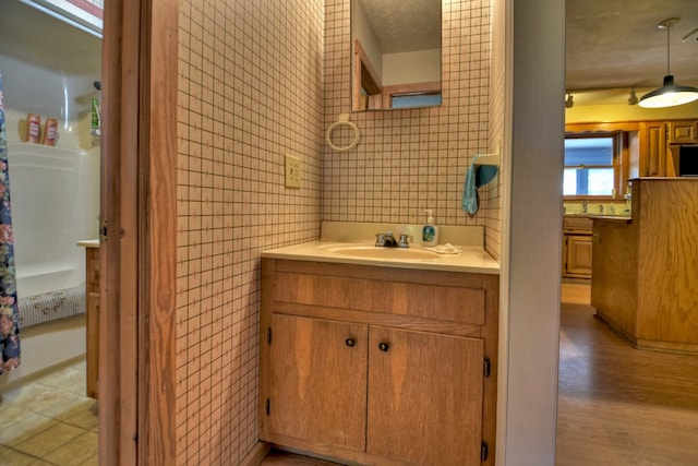 bathroom featuring wood-type flooring, vanity, and tile walls