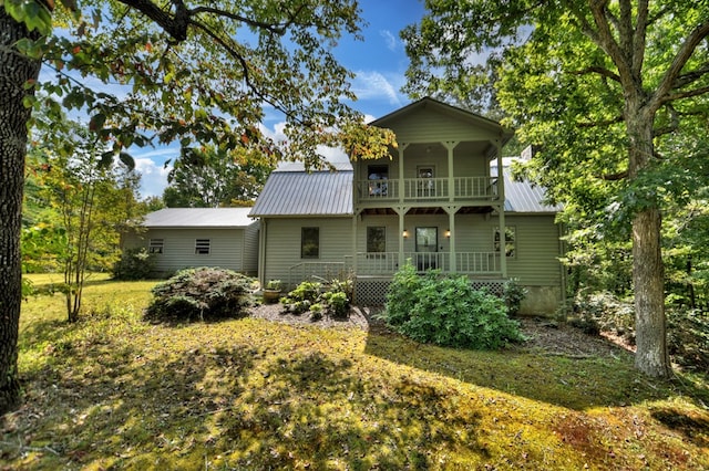 rear view of property featuring a balcony, covered porch, and a lawn