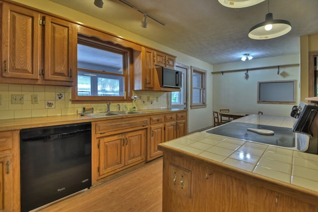 kitchen with sink, black appliances, tile counters, light hardwood / wood-style floors, and decorative backsplash