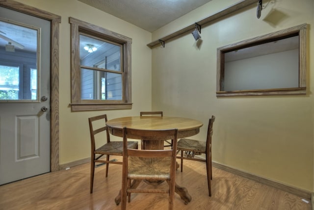 dining space featuring light wood-type flooring and a textured ceiling