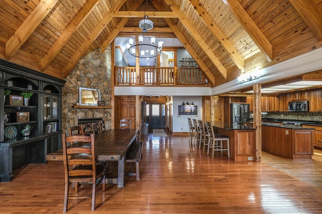 dining room featuring wood-type flooring, wooden ceiling, a fireplace, and an inviting chandelier