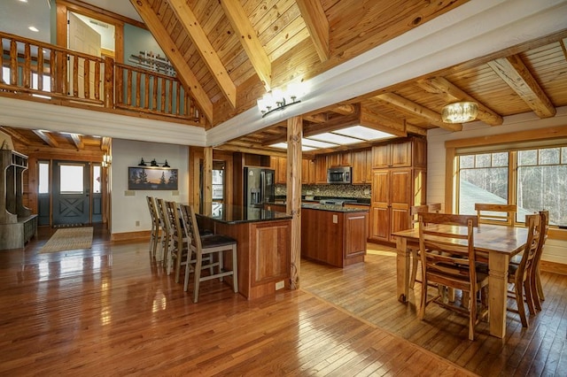 dining room featuring plenty of natural light, wooden ceiling, light hardwood / wood-style floors, and beamed ceiling