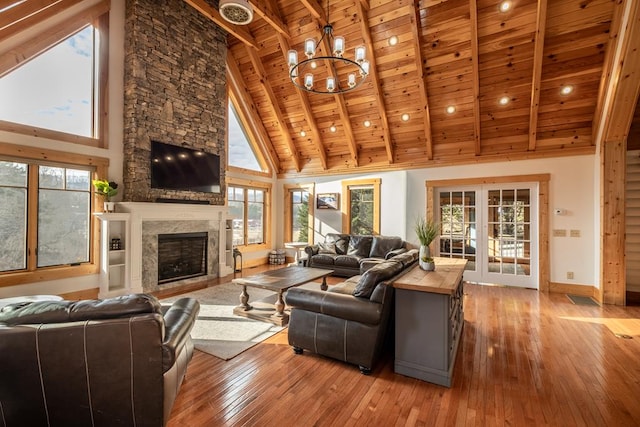 living room with a fireplace, wood ceiling, light hardwood / wood-style floors, beam ceiling, and french doors