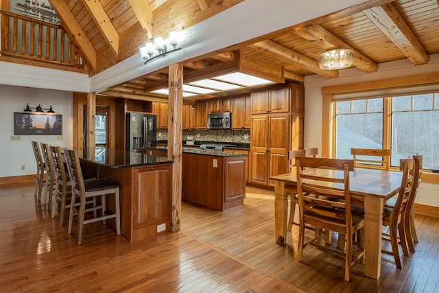 kitchen featuring wooden ceiling, appliances with stainless steel finishes, a kitchen island, and light hardwood / wood-style flooring