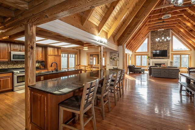 dining area featuring dark wood-type flooring, a large fireplace, beam ceiling, and sink