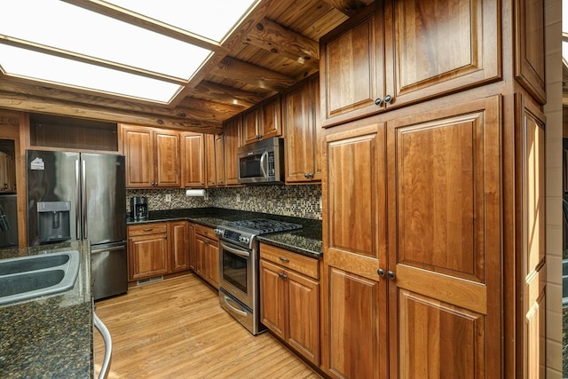 kitchen with appliances with stainless steel finishes, tasteful backsplash, dark stone counters, wood ceiling, and light hardwood / wood-style floors