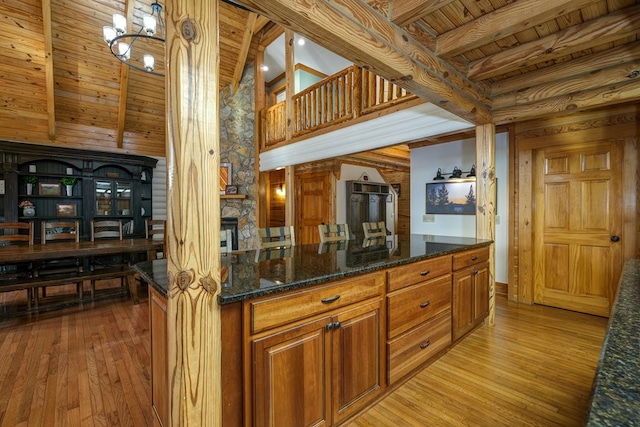 kitchen featuring light hardwood / wood-style floors, pendant lighting, wood ceiling, and dark stone counters