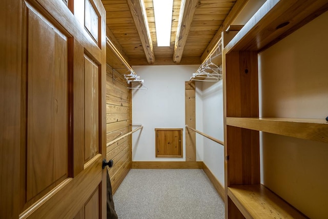 walk in closet featuring beamed ceiling and light carpet