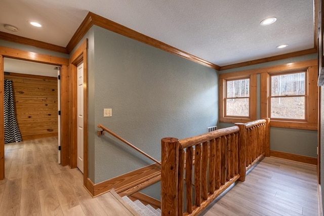 staircase with hardwood / wood-style floors, ornamental molding, and a textured ceiling