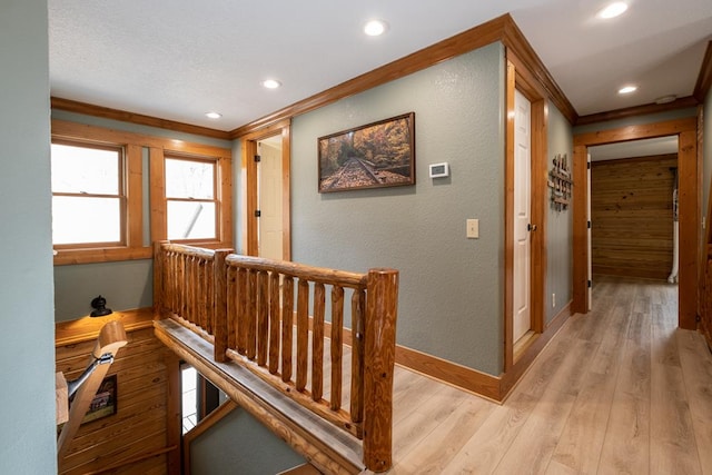 hallway with ornamental molding and light hardwood / wood-style floors