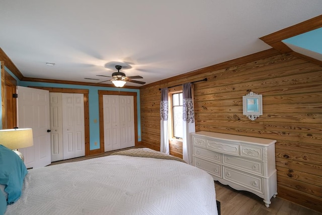 unfurnished bedroom with ceiling fan, light wood-type flooring, and two closets