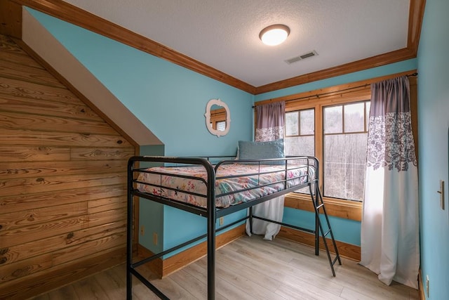 bedroom featuring crown molding, a textured ceiling, and light hardwood / wood-style floors