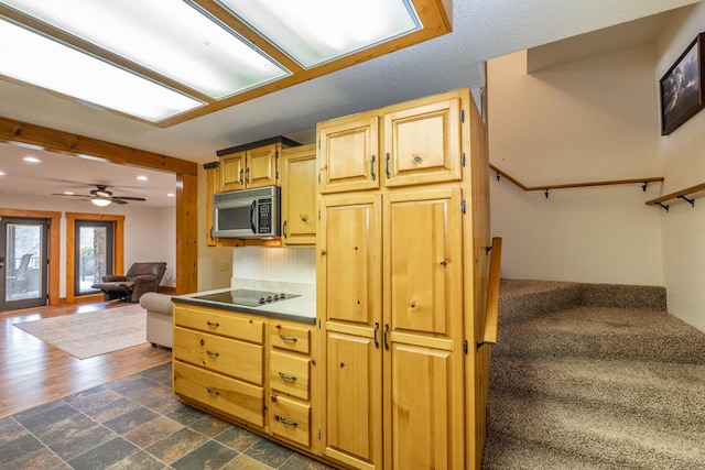 kitchen featuring black electric stovetop, ceiling fan, and light brown cabinets