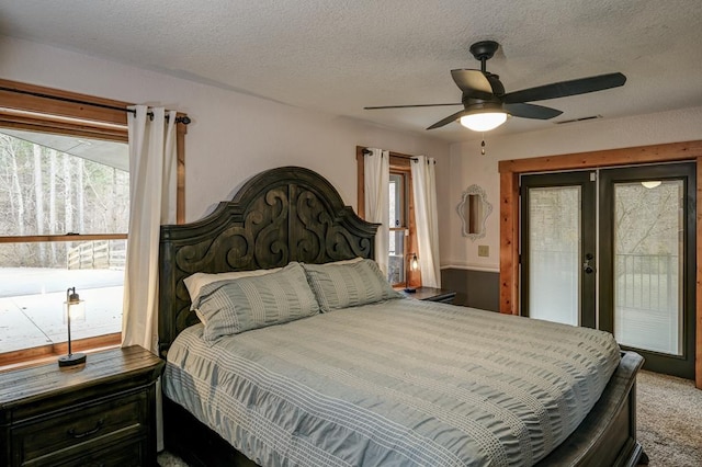 carpeted bedroom featuring ceiling fan, access to outside, a textured ceiling, and french doors