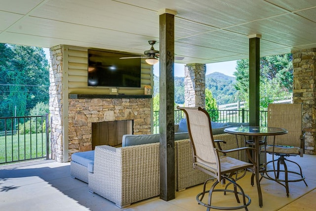 view of patio / terrace featuring ceiling fan and a stone fireplace