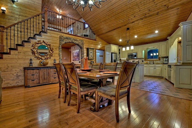 dining space featuring wooden ceiling, light hardwood / wood-style floors, a towering ceiling, and a notable chandelier