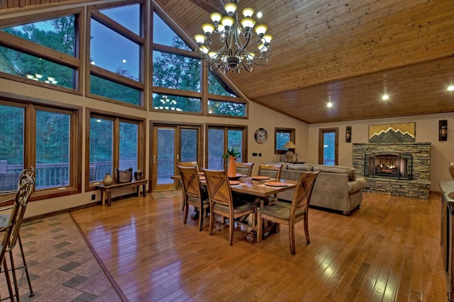 dining space with wood ceiling, a fireplace, wood-type flooring, high vaulted ceiling, and a chandelier