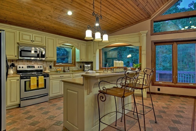 kitchen with appliances with stainless steel finishes, decorative backsplash, decorative light fixtures, a chandelier, and cream cabinets