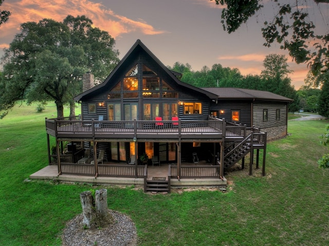 back house at dusk with a wooden deck, a lawn, and a patio