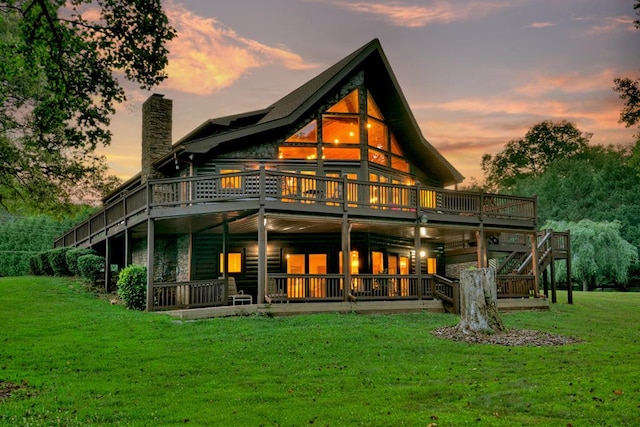 back house at dusk featuring a deck and a yard