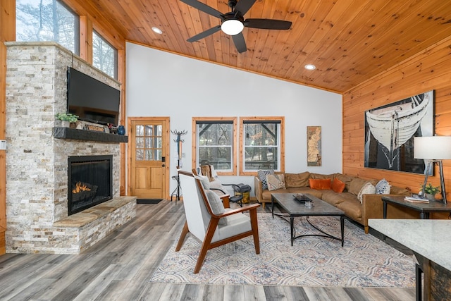 living room with ceiling fan, wooden ceiling, a stone fireplace, high vaulted ceiling, and hardwood / wood-style flooring