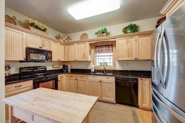 kitchen with black appliances, light brown cabinets, butcher block counters, light hardwood / wood-style floors, and sink