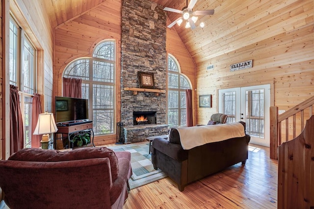 living room featuring high vaulted ceiling, a wealth of natural light, a stone fireplace, and wood ceiling