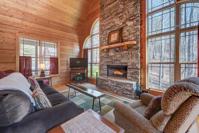 living room with high vaulted ceiling, wood-type flooring, a fireplace, and wood walls