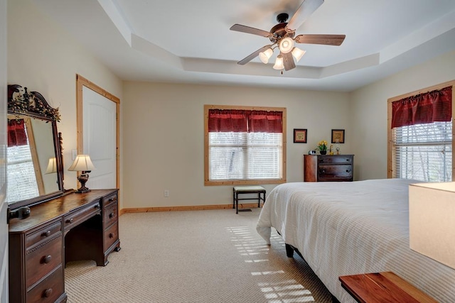 carpeted bedroom featuring ceiling fan and a raised ceiling