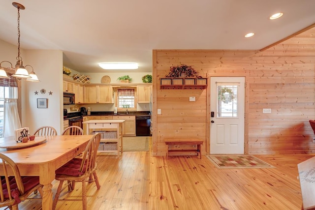 dining area with a wealth of natural light, light hardwood / wood-style flooring, and wooden walls