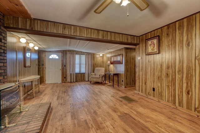 foyer entrance with visible vents, ceiling fan, wood finished floors, and wooden walls