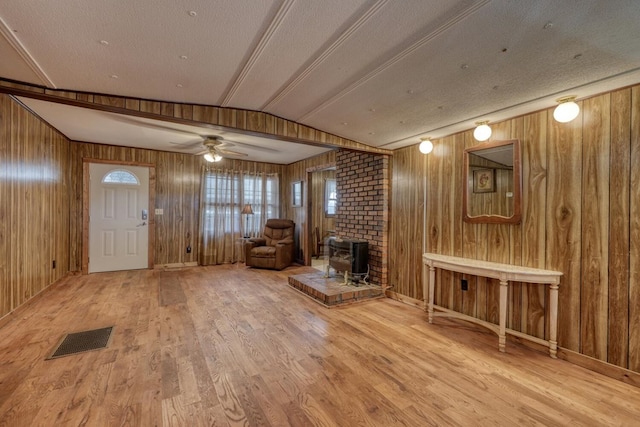 entrance foyer featuring a ceiling fan, wood walls, wood finished floors, and visible vents