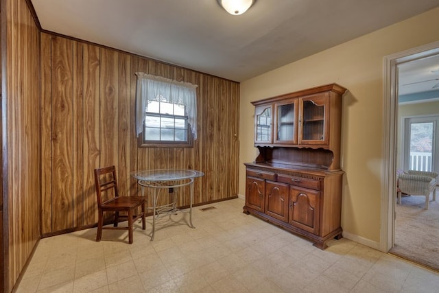 living area with baseboards, wood walls, and light floors