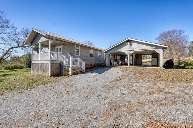 view of front of home with a detached carport, driveway, covered porch, and stairway