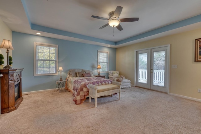 carpeted bedroom featuring french doors, access to exterior, a fireplace, a raised ceiling, and recessed lighting