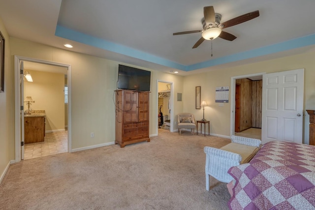 bedroom featuring light carpet, recessed lighting, baseboards, a tray ceiling, and a spacious closet