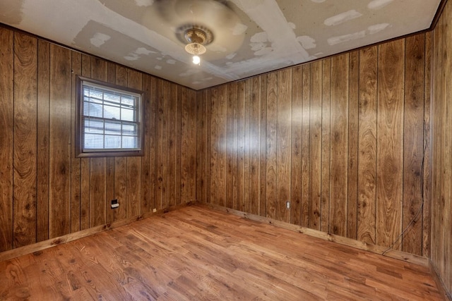 unfurnished room featuring baseboards, wood walls, and wood finished floors